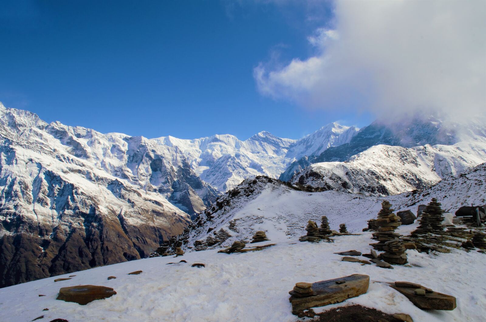 Snowy ridge with stone cairns in the foreground and peaks beyond